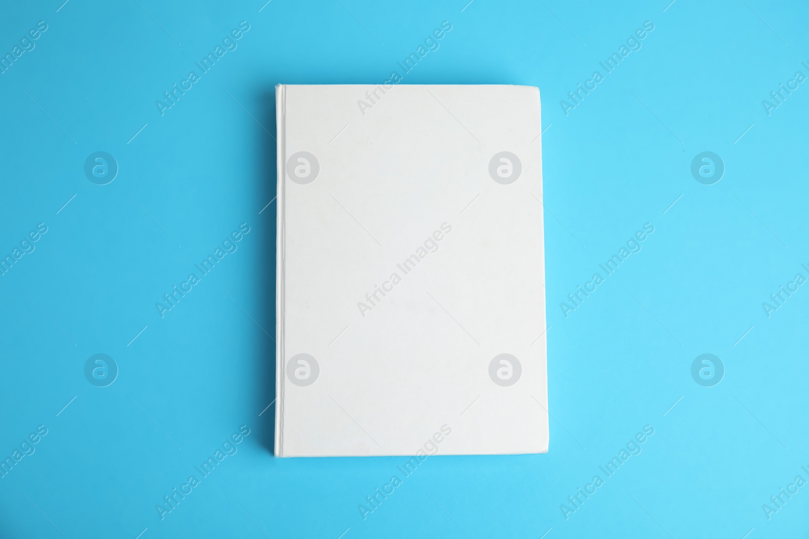 Photo of Book with blank cover on blue background, top view