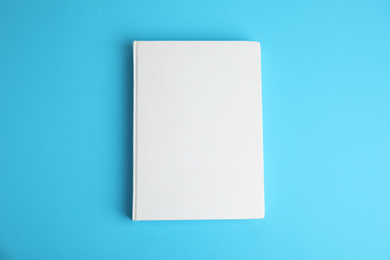 Book with blank cover on blue background, top view