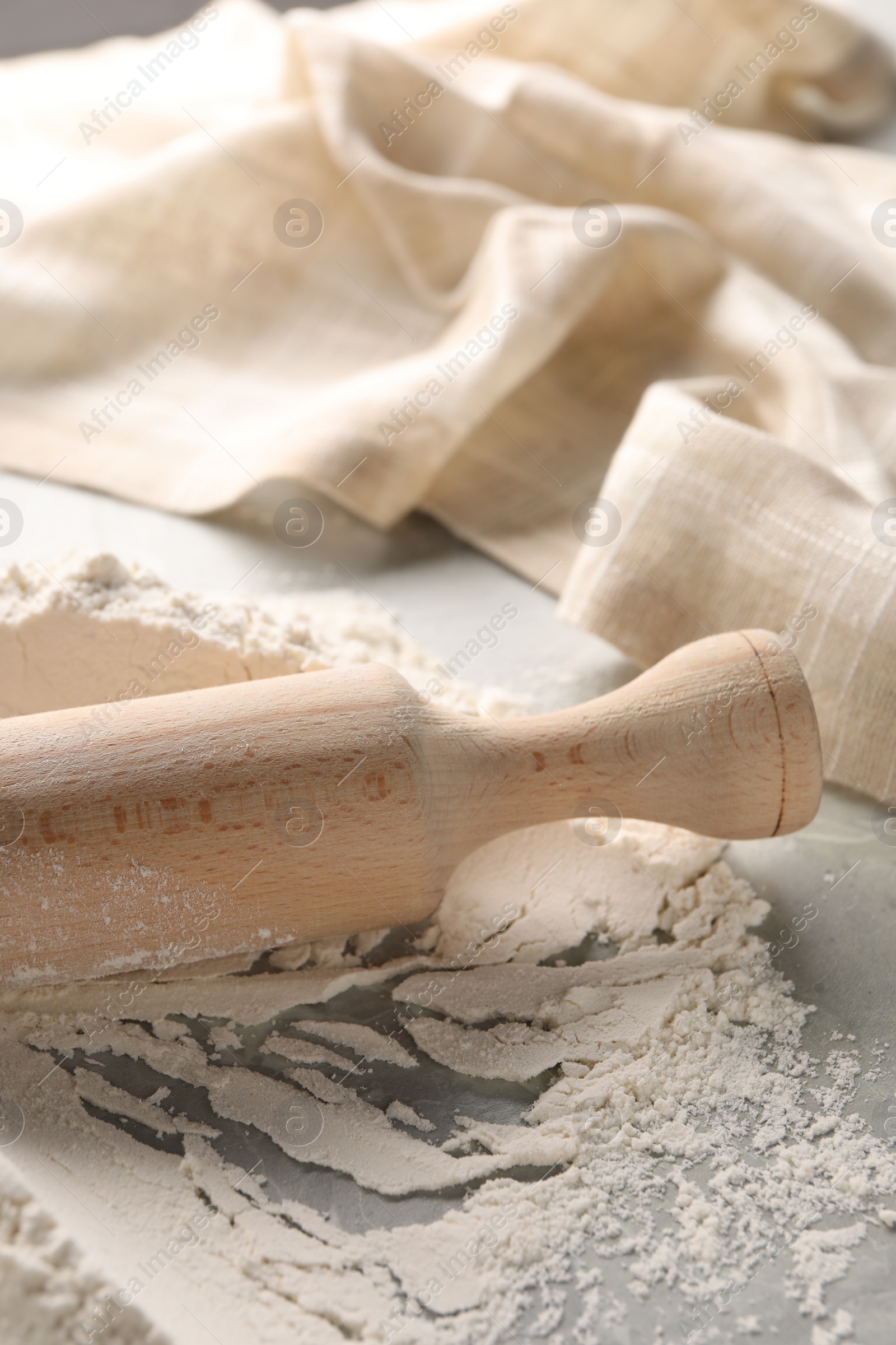 Photo of Pile of flour and rolling pin on grey marble table, closeup