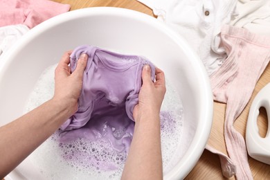 Photo of Woman washing baby clothes in basin on floor, closeup