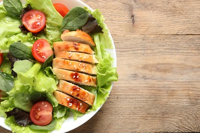 Photo of Delicious salad with chicken, cherry tomato and spinach on wooden table, top view. Space for text