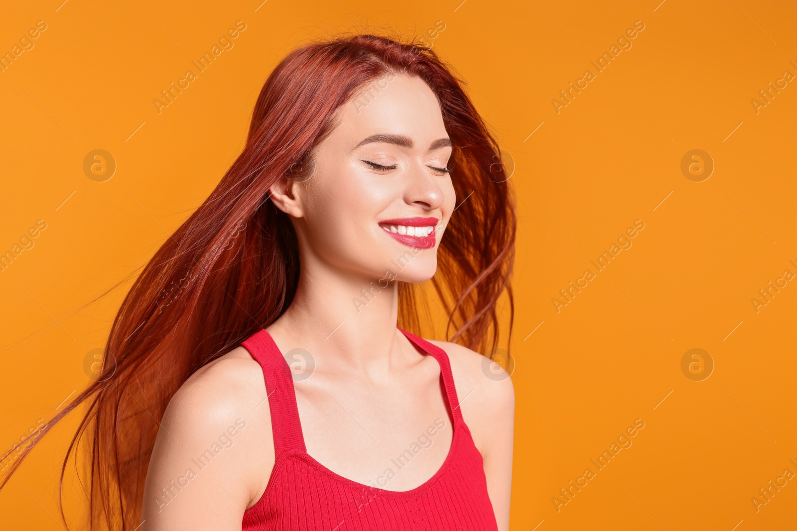 Photo of Happy woman with red dyed hair on orange background