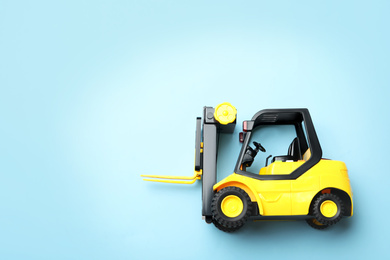 Photo of Top view of toy forklift on blue background, space for text. Logistics and wholesale concept