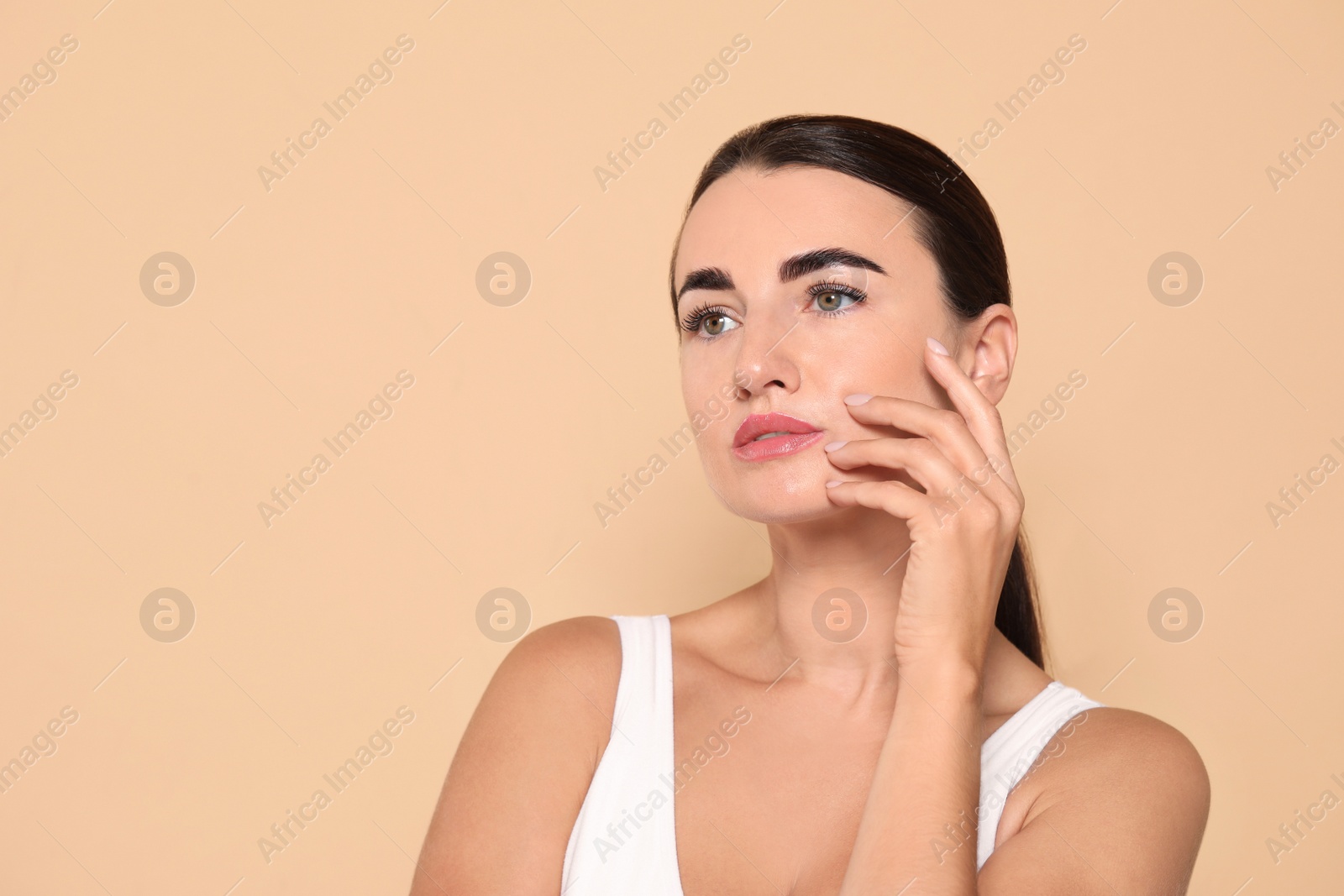 Photo of Beautiful woman with perfect skin under eyes on beige background. Space for text