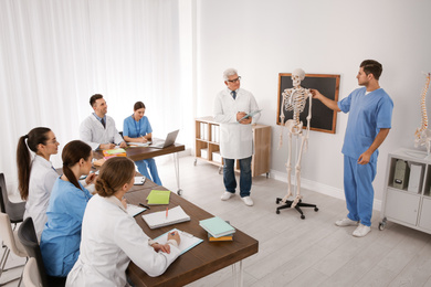 Photo of Medical students and professor studying human skeleton anatomy in classroom
