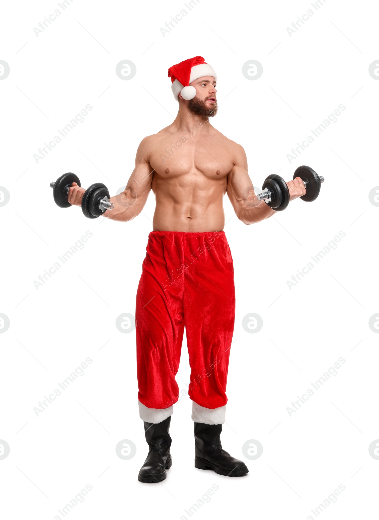 Photo of Attractive young man with muscular body in Santa hat holding dumbbells on white background