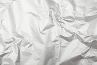 Crumpled silver foil as background, top view