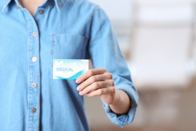 Photo of Woman holding business card indoors, closeup with space for text. Medical service