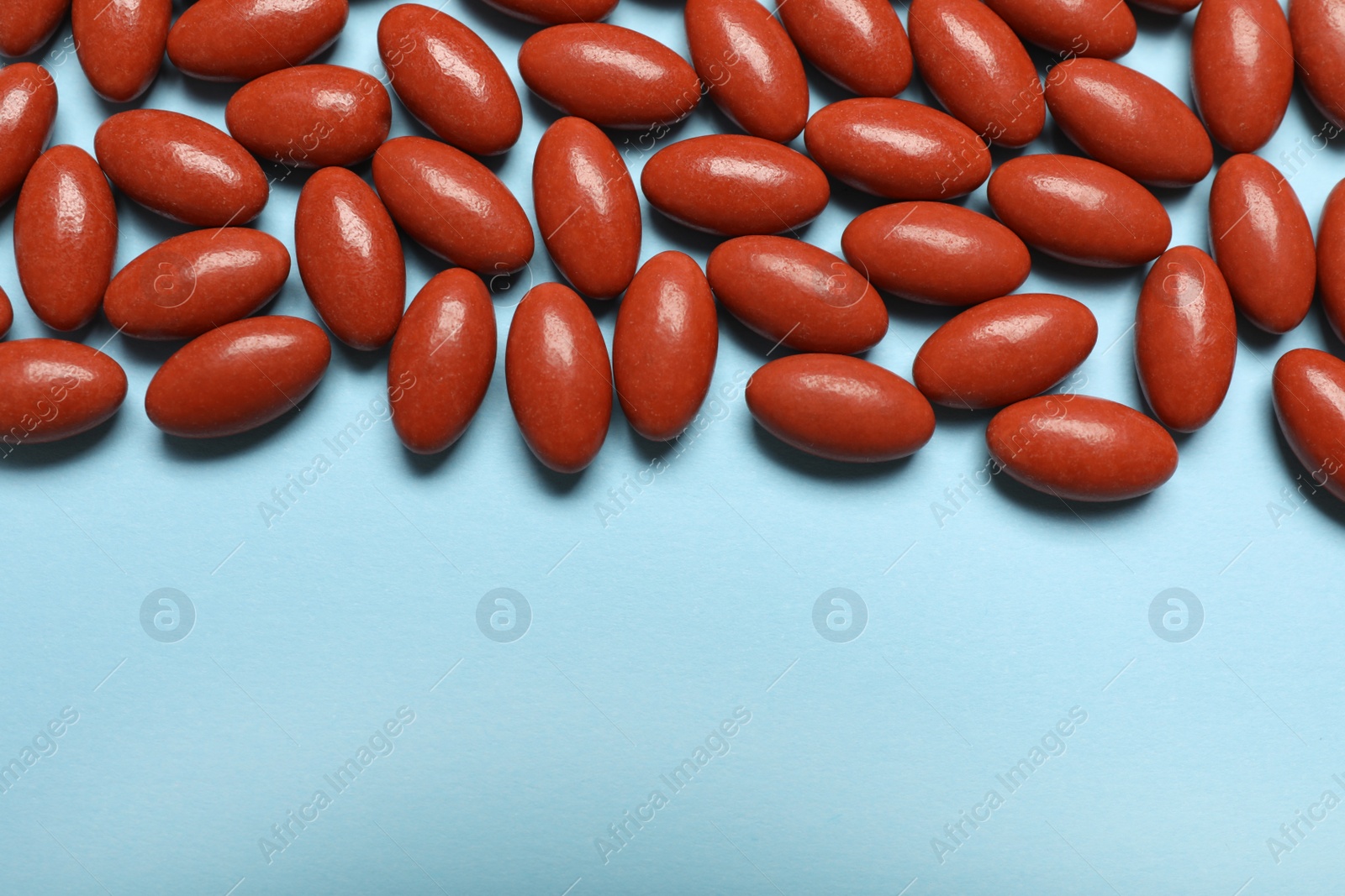 Photo of Brown pills and space for text on light blue background, flat lay. Anemia concept