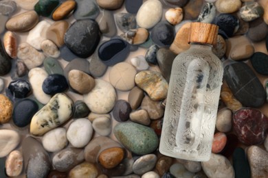 Photo of Bottle of cosmetic product on wet stones, top view. Space for text