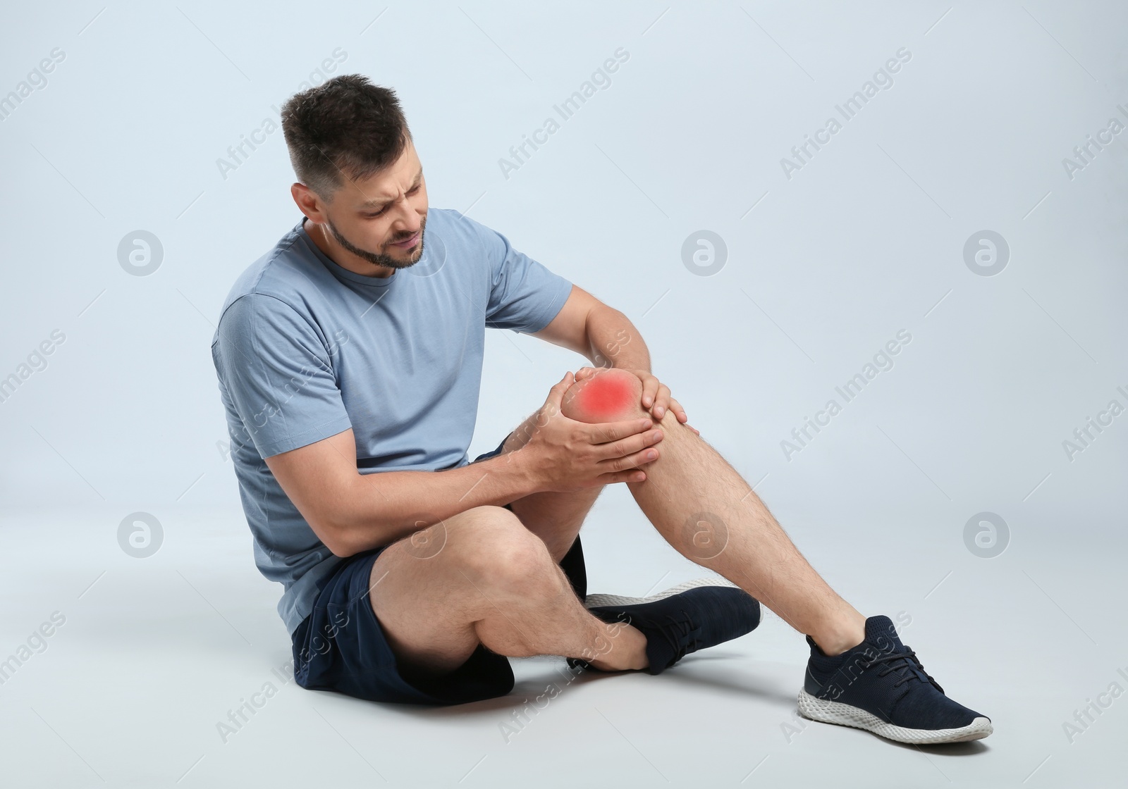 Photo of Full length portrait of man with knee problems sitting on grey background