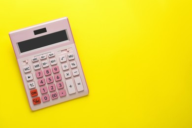 Pink calculator on yellow background, top view. Space for text