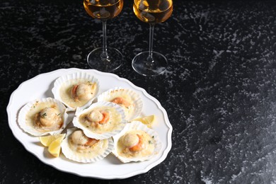 Fried scallops in shells and wine on black textured table, space for text