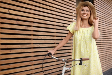 Photo of Young woman with bicycle against wooden wall