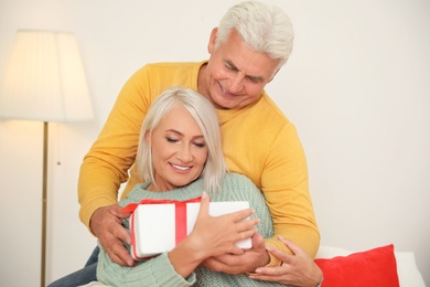 Photo of Happy mature couple with Christmas gift at home