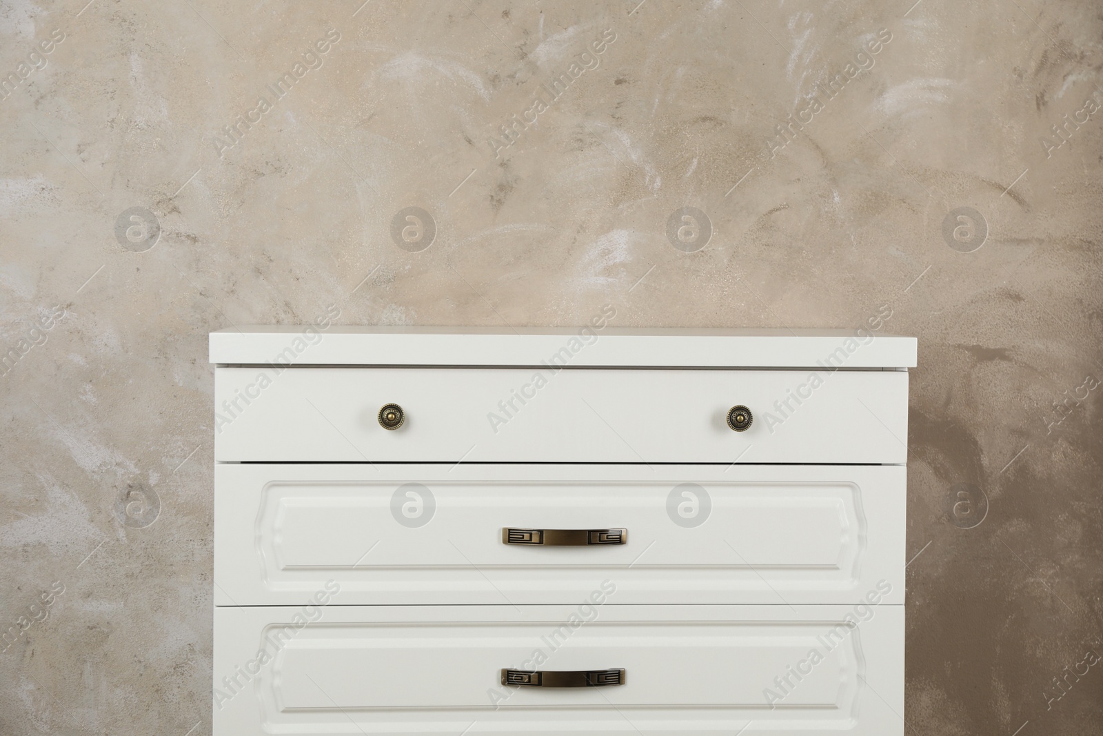 Photo of Modern chest of drawers near beige wall