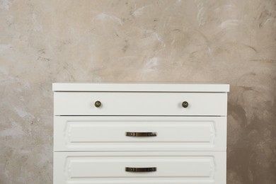 Modern chest of drawers near beige wall