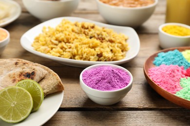 Photo of Traditional Indian food and color powders on wooden table. Holi festival celebration
