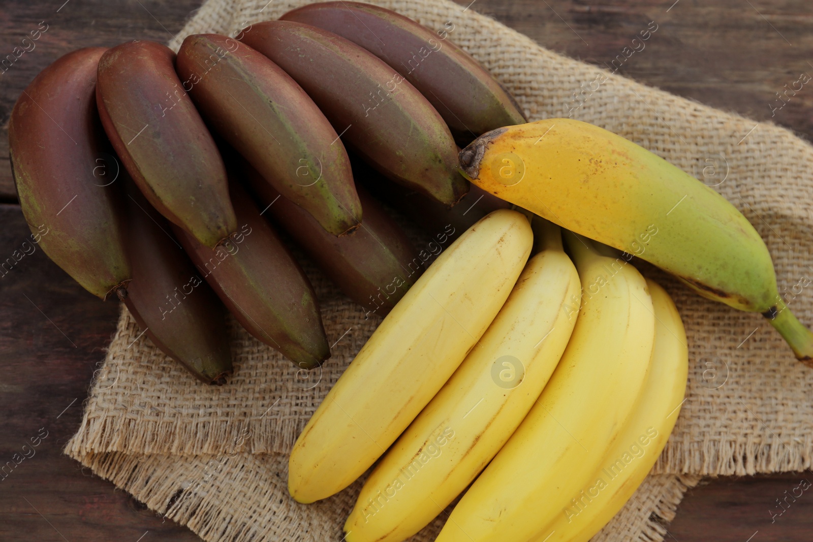 Photo of Different sorts of bananas on wooden table, top view