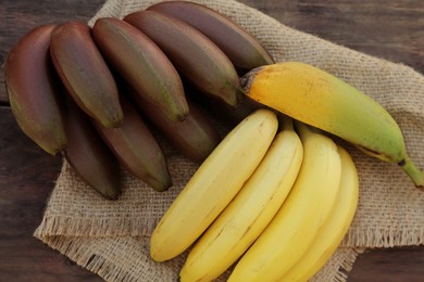 Different sorts of bananas on wooden table, top view