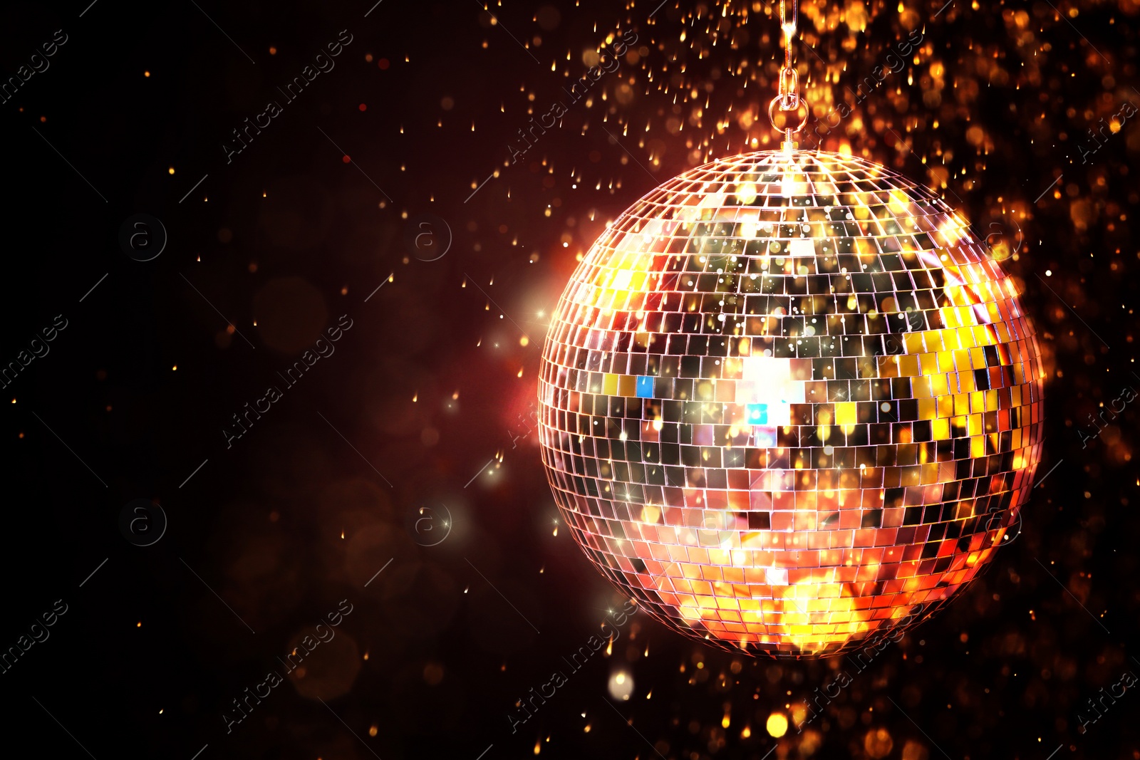 Image of Shiny disco ball under golden lights on dark background, space for text. Bokeh effect