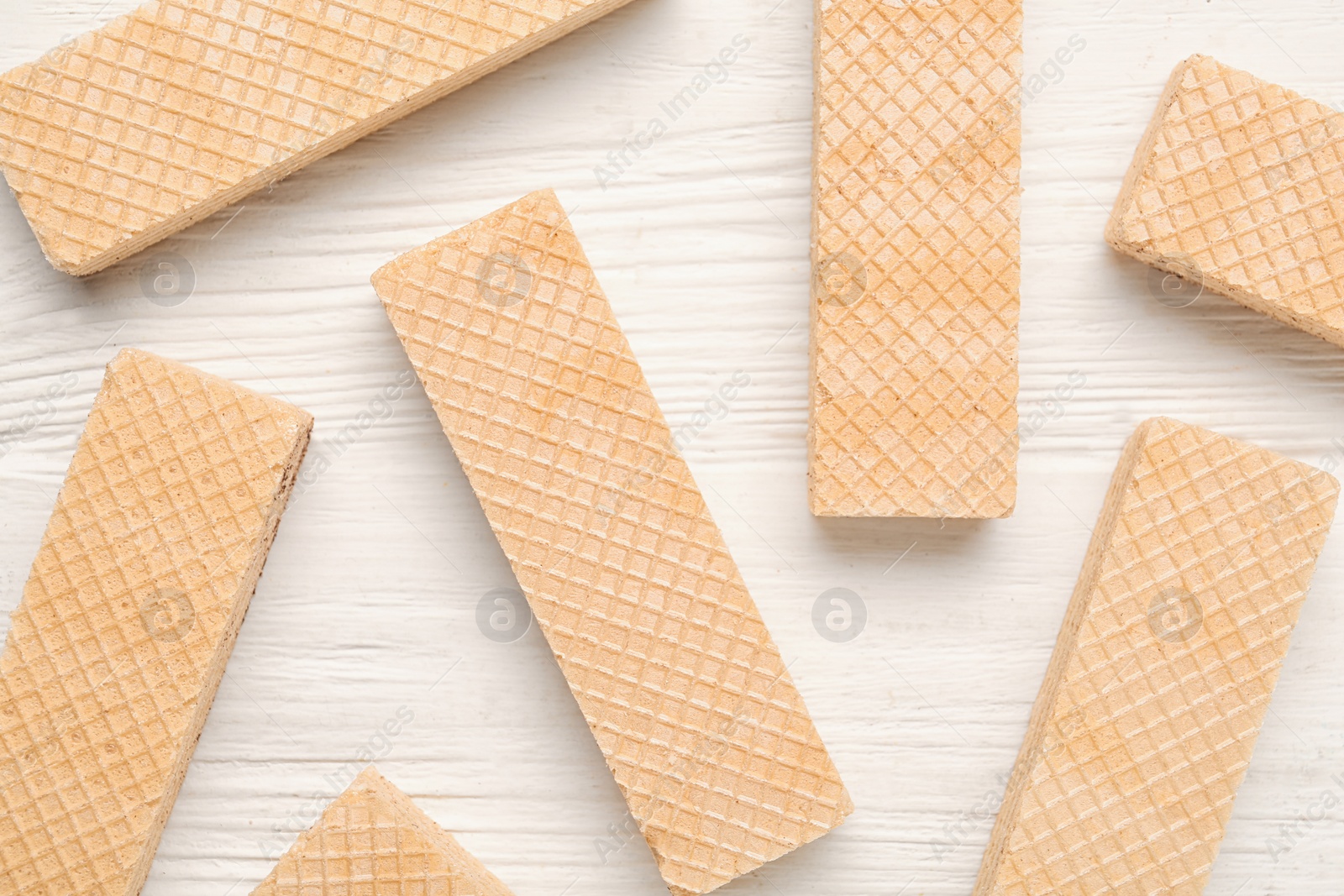 Photo of Tasty wafer sticks on white wooden table, flat lay