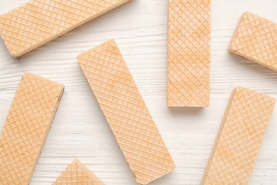 Tasty wafer sticks on white wooden table, flat lay