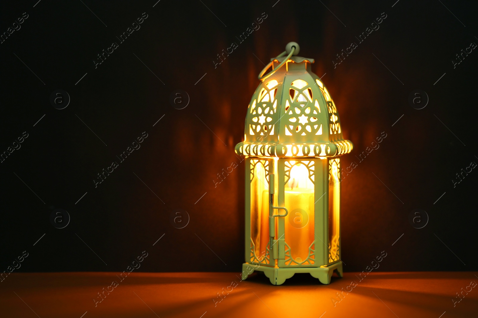 Photo of Decorative Arabic lantern on table against dark background. Space for text