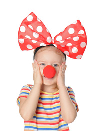 Photo of Little girl with large bow and clown nose on white background. April fool's day