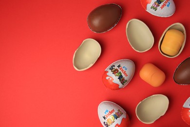 Photo of Sveti Vlas, Bulgaria - June 29, 2023: Kinder Surprise Eggs and plastic capsules on red background, flat lay. Space for text