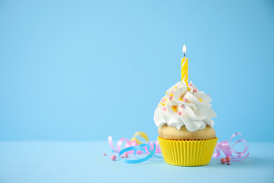 Photo of Delicious birthday cupcake with candle on light blue background. Space for text