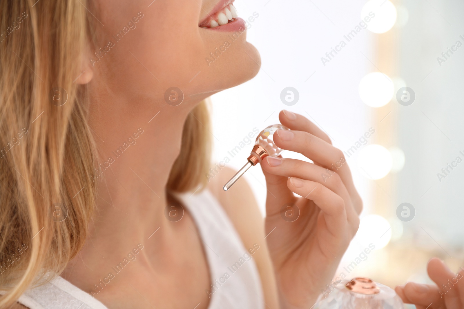 Photo of Young woman applying perfume near mirror indoors, closeup
