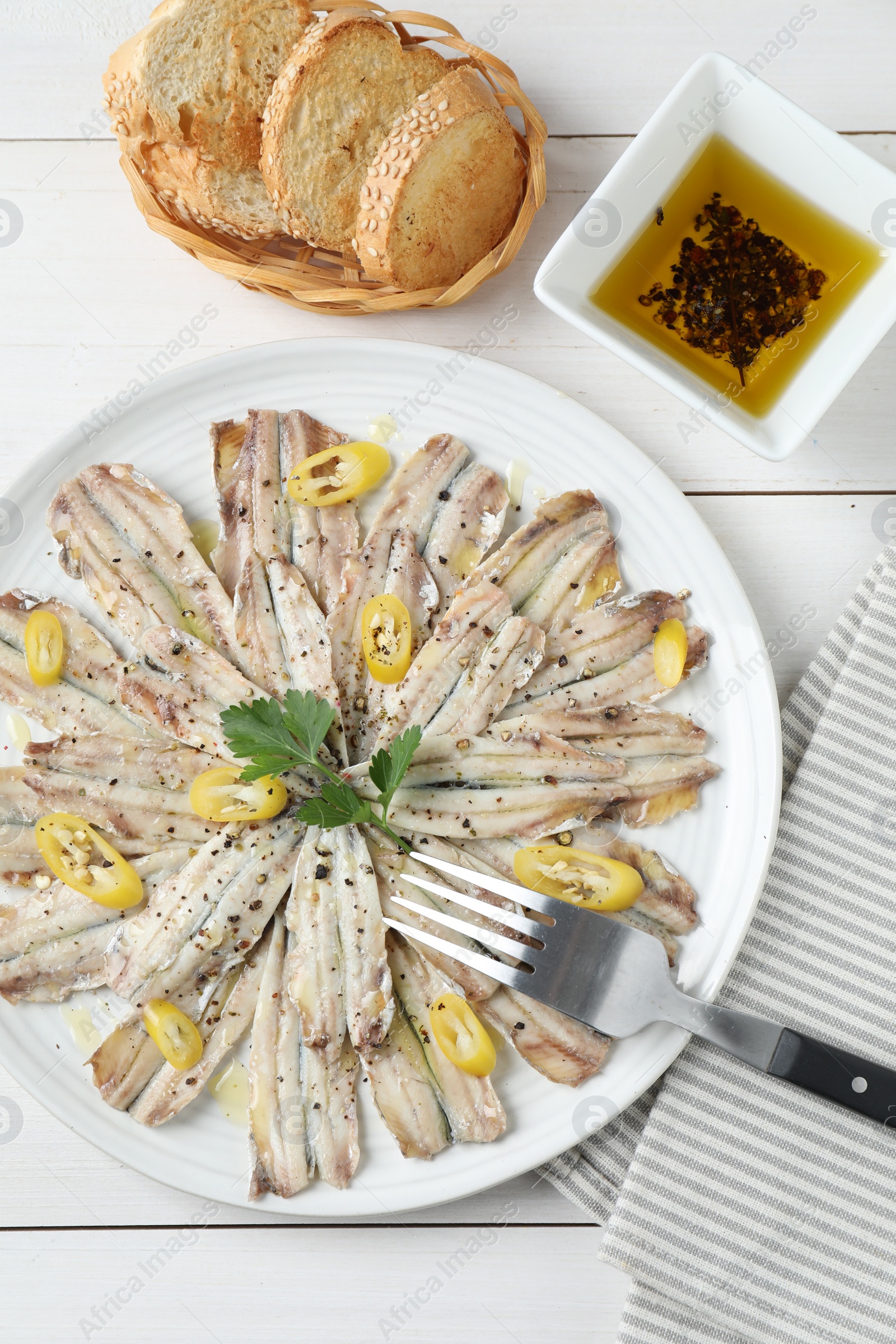 Photo of Tasty pickled anchovies served on white wooden table, flat lay