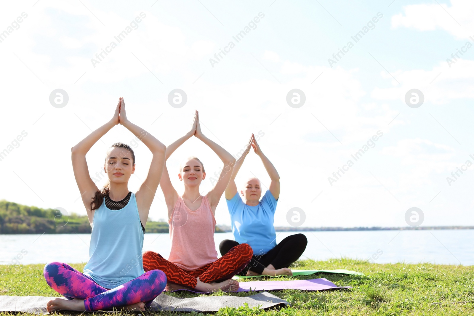 Photo of Group of women practicing yoga near river on sunny day