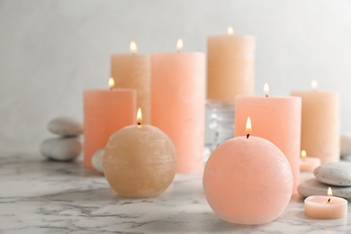 Composition of burning candles and spa stones on table. Space for text