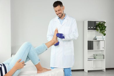 Photo of Male orthopedist fitting insole to patient's foot in hospital