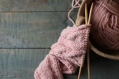 Soft pink woolen yarn, knitting and needles on wooden table, top view. Space for text