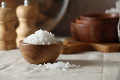 Photo of Organic salt in wooden bowl on table, closeup. Space for text