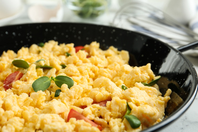 Tasty scrambled eggs with sprouts and cherry tomato in wok pan on table, closeup