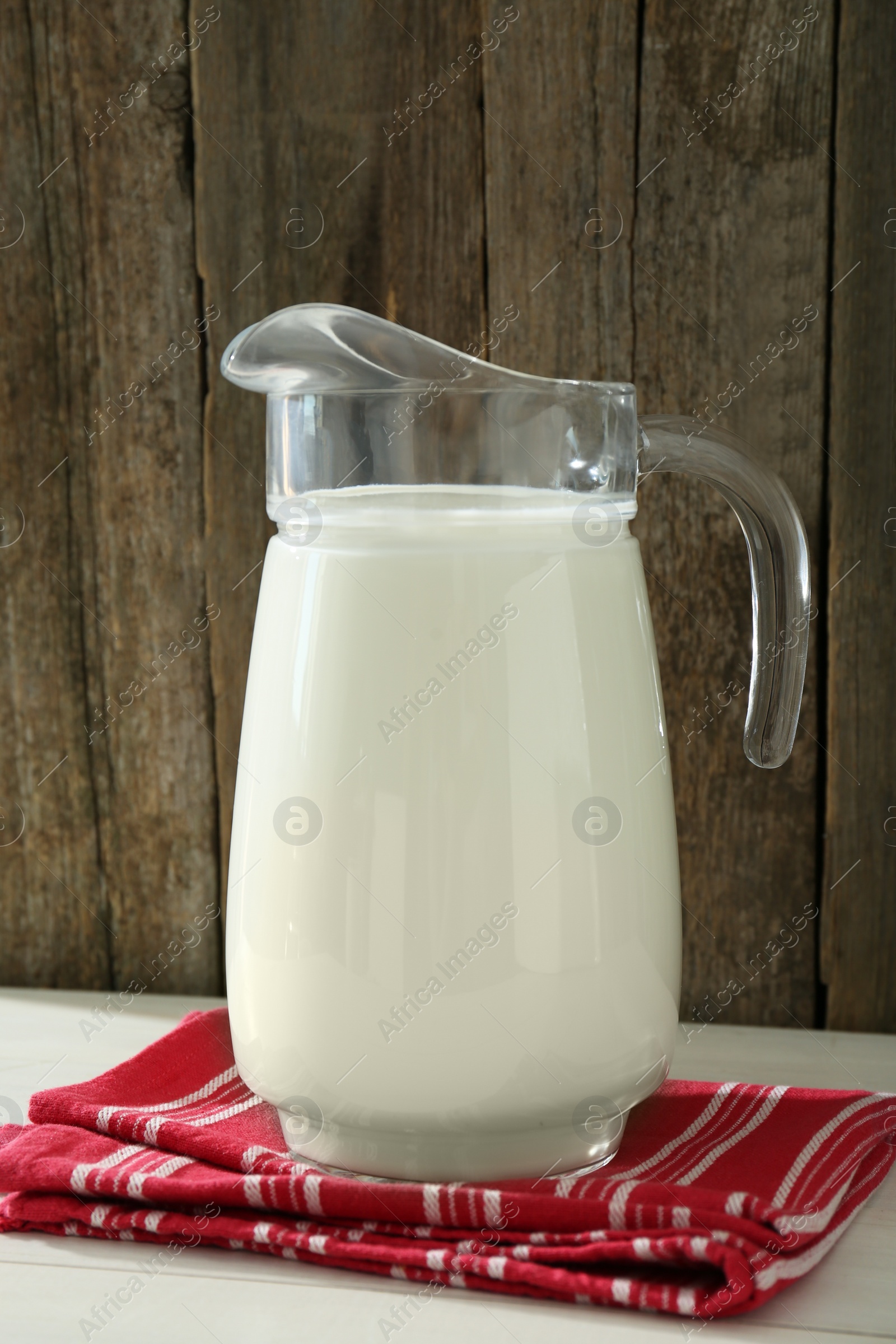 Photo of Jug of fresh milk on white wooden table