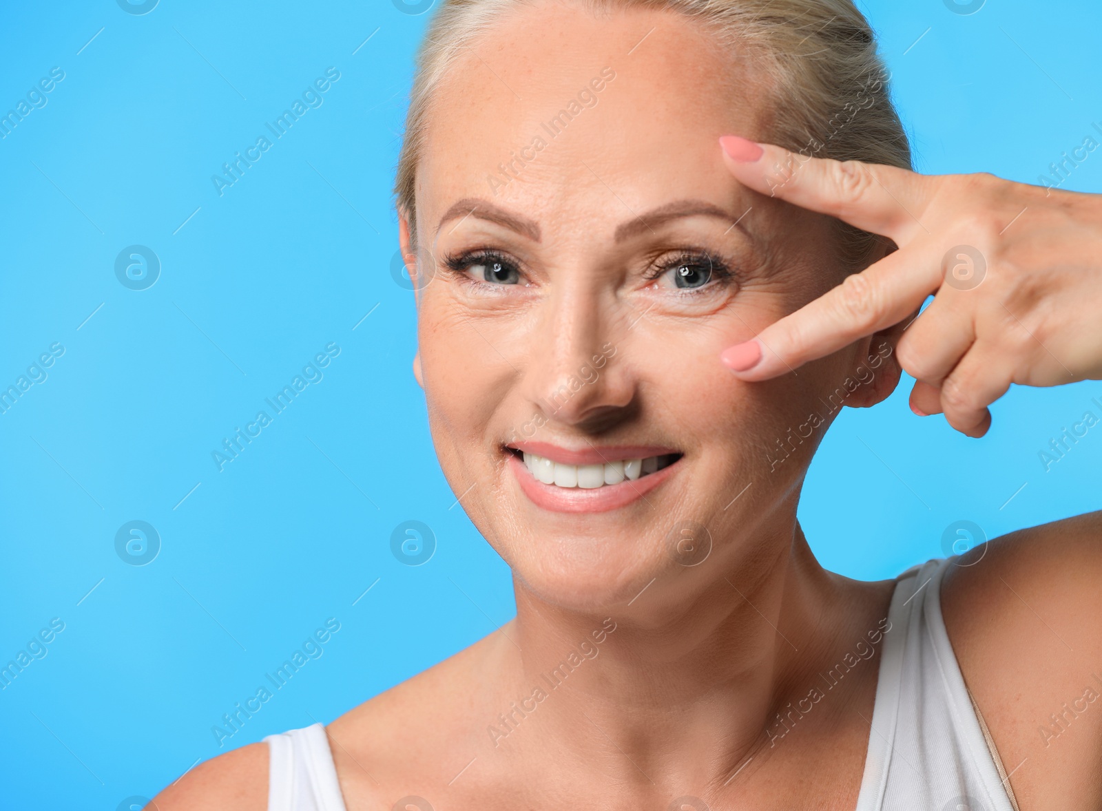 Photo of Portrait of beautiful mature woman with perfect skin on light blue background