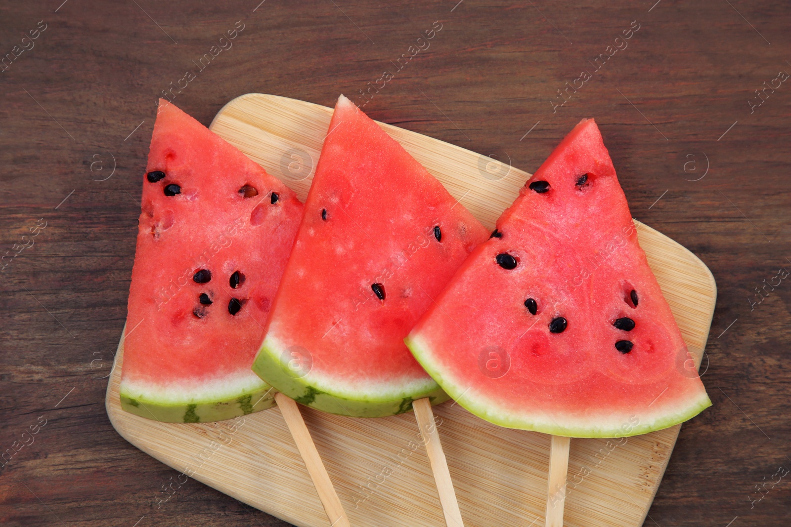 Photo of Slices of delicious ripe watermelon on wooden table, top view