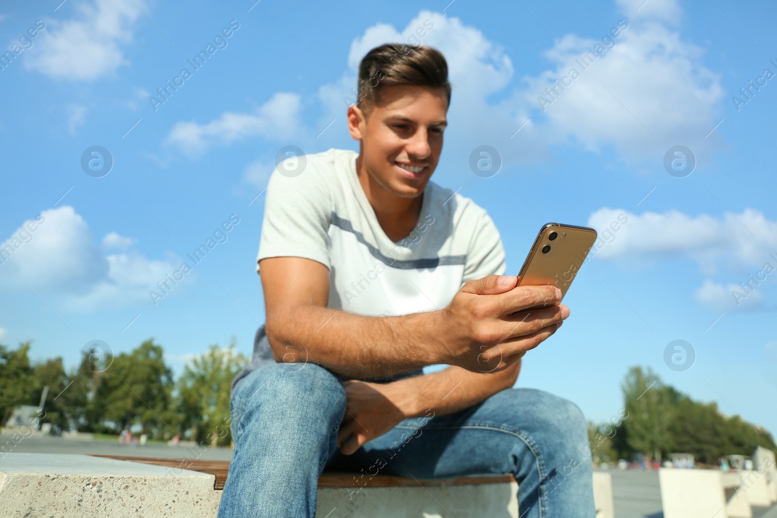 Photo of Handsome man using modern mobile phone outdoors, focus on hand