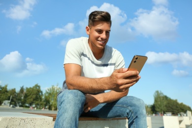 Photo of Handsome man using modern mobile phone outdoors, focus on hand