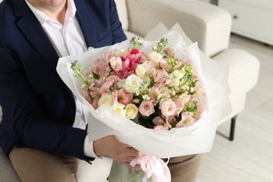 Man with beautiful bouquet of flowers on sofa indoors, closeup