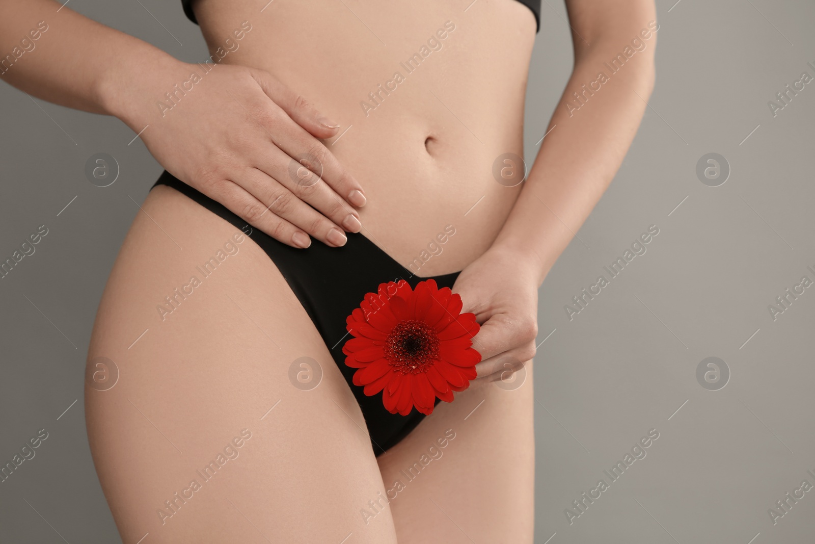 Photo of Gynecology. Woman in underwear with gerbera flower on grey background, closeup