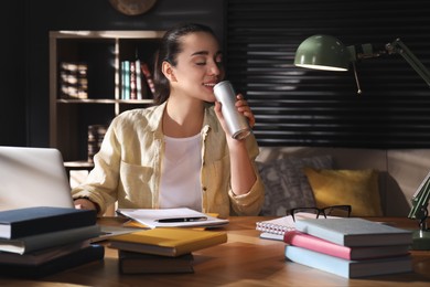 Photo of Young woman with energy drink studying at home