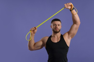 Photo of Muscular man exercising with elastic resistance band on purple background. Space for text