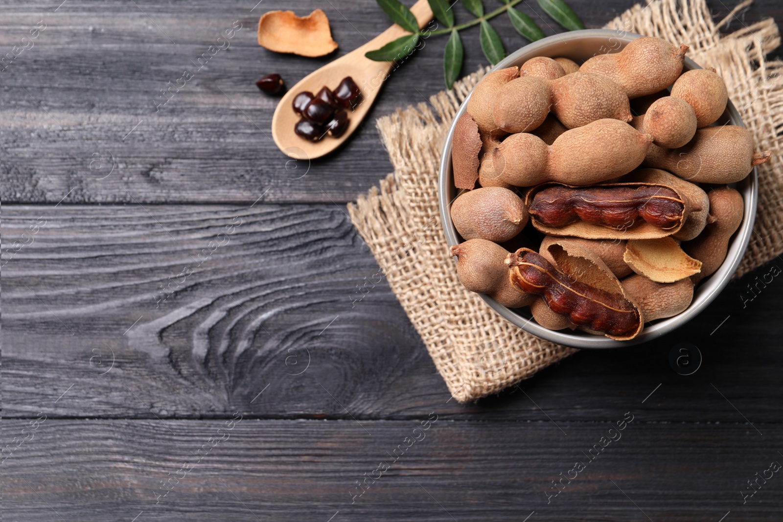 Photo of Delicious ripe tamarinds on black wooden table, flat lay. Space for text