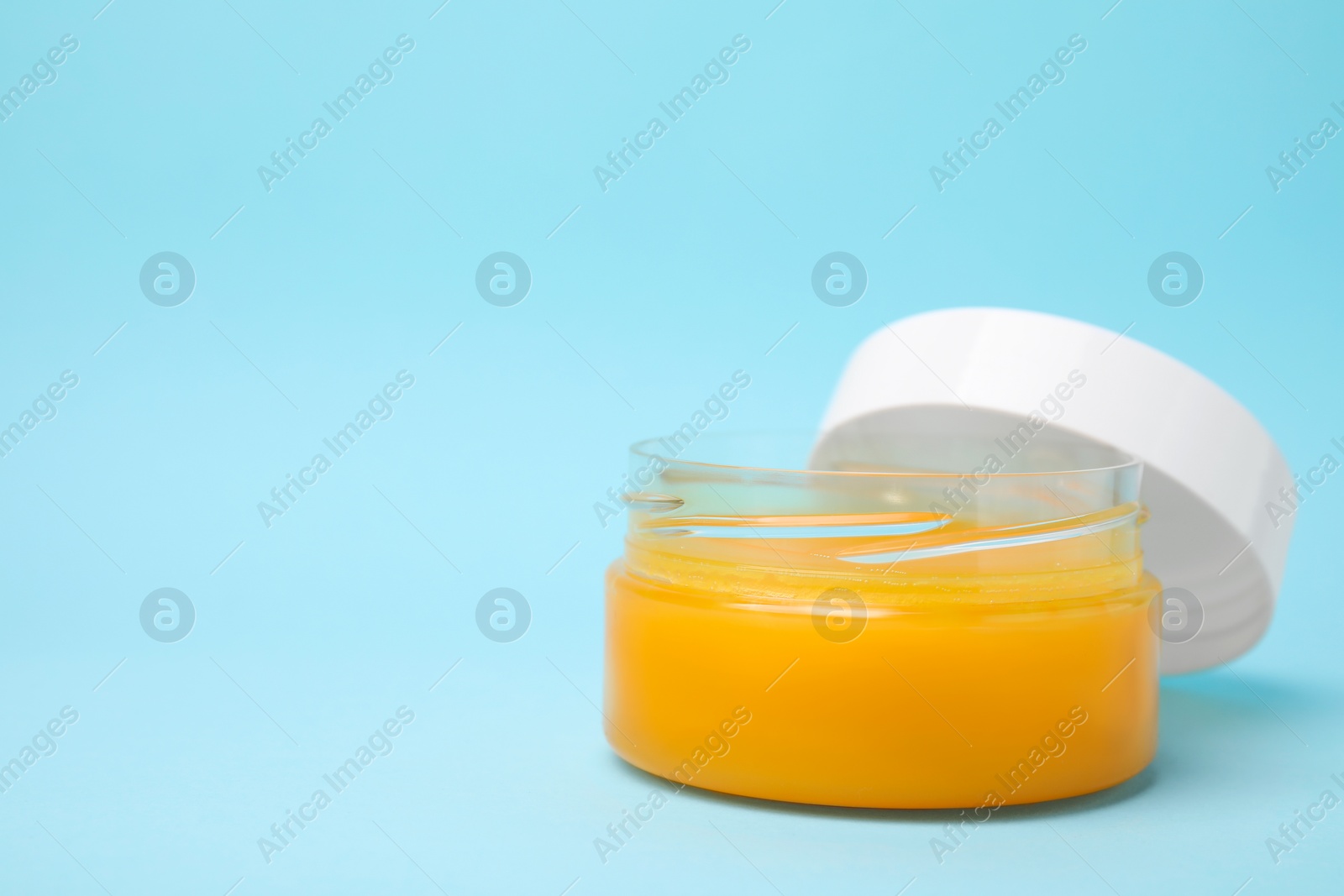 Photo of Open jar of petrolatum on light blue background. Space for text